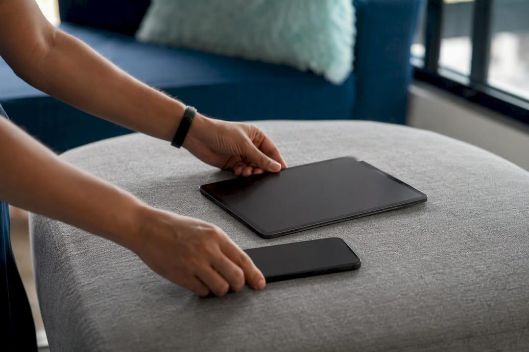 Hands holding tablet and smartphone side by side